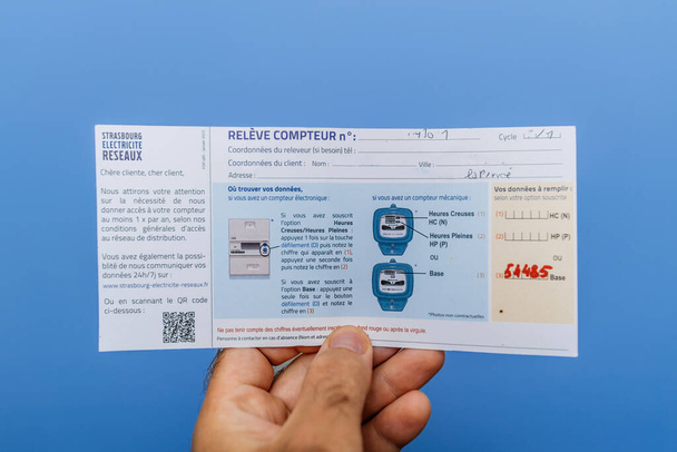 París, Francia - 1 de septiembre de 2023: Aviso de Strasbourg Electricite Reseaux solicitando datos para la lectura del medidor de potencia, titulado Avis de Passage, sobre un fondo azul - Foto, Imagen