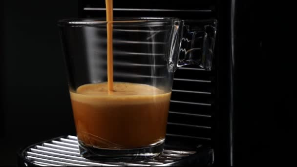 Café negro con espuma. Elaboración de café negro espresso o ristretto en cápsulas automáticas de cafetera. De cerca. Fondo oscuro - Metraje, vídeo