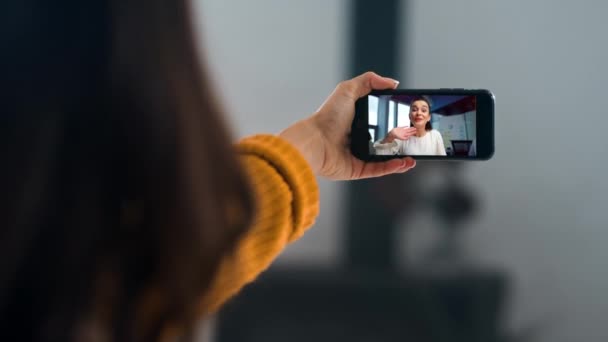 Απομακρυσμένες γυναίκες που μιλούν βιντεοδιάσκεψη από το smartphone. Κοντινό πλάνο κορίτσι χέρια κρατώντας το κινητό τηλέφωνο κυματίζει οθόνη. Άγνωστη κυρία καλεί φίλη μοιράζονται τα νέα στο σπίτι Σαββατοκύριακο. Χαμογελαστοί φίλοι επικοινωνούν online - Πλάνα, βίντεο