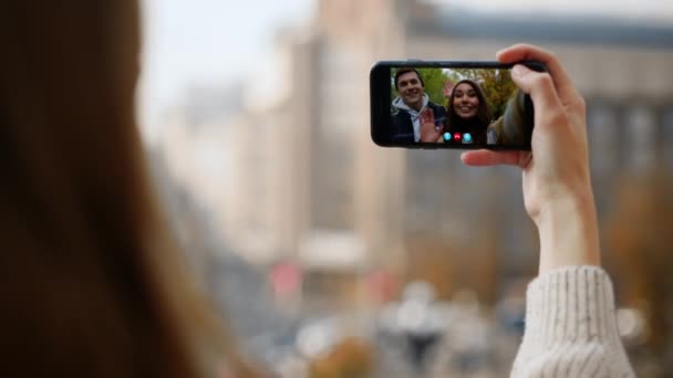 Žena ruka videokonzervovat smartphone přátelé na ulici detailní. Šťastný pár mávající sdílení obrazovky novinky ve virtuální konferenční aplikaci. Neznámá dívka mluví online komunikace s rodinou na výlet dovolená - Záběry, video