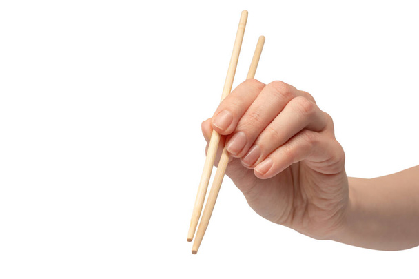 Mano femminile che tiene bacchette di sushi in legno isolate su uno sfondo bianco.  - Foto, immagini