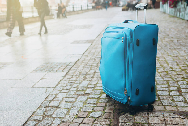 Cestovní zavazadla prázdné evropské ulice. Cestovní ruch, modrý kufr na dlážděné ulici, deštivé počasí. - Fotografie, Obrázek
