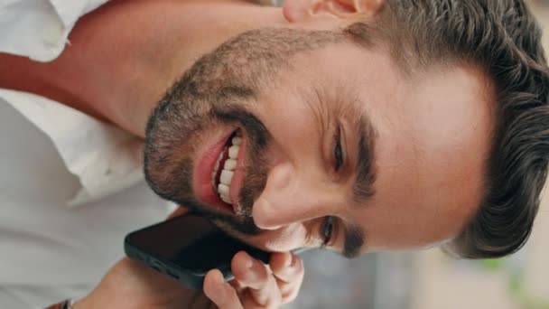 Веселий чоловік, який розмовляє клітиною, ділиться добрими новинами в місті, вертикально орієнтованому крупним планом. Щасливий латинський фрілансер сміється за викликом смартфона, відпочиваючи в кафетерії. усміхнений елегантний бізнесмен розмовляє мобільним телефоном - Кадри, відео