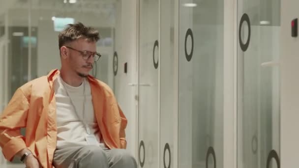 Kerekesszékkel közlekedő fiatalember a coworking office folyosóján, belépőkártyával nyitott ajtó és belépő a tárgyalóba - Felvétel, videó