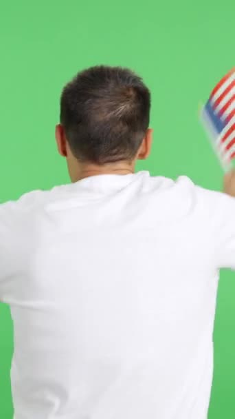 Wideo w studiu z chromą tylnego widoku mężczyzny machającego prostopadłem do Stanów Zjednoczonych - Materiał filmowy, wideo