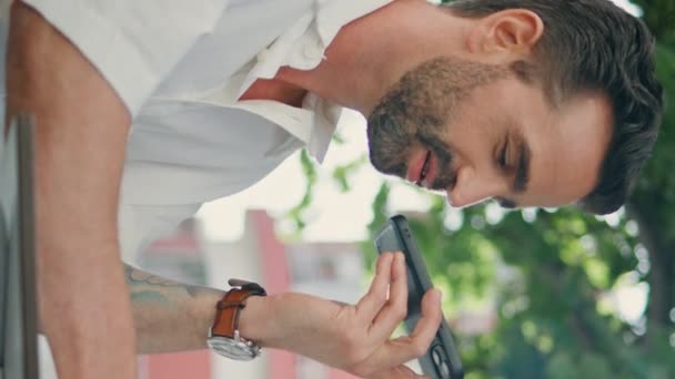Lateinischer Mann, der eine Sprachnachricht beim Kaffeetrinken in vertikaler Nahaufnahme aufnimmt. Schöner Freiberufler, der Handy-Audio-Benachrichtigungen verschickt. Bärtiger Manager diktiert Antrag auf Assistenzbewerbung - Filmmaterial, Video