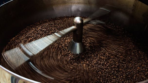 Braune Kaffeebohnen und geröstete Spinndecke professionelle Maschine, Nahaufnahme bis zum weichen Fokus, machen Sie Fotos mit niedriger Geschwindigkeit, um Bewegung und Kaffeebohnen Detailkonzept benötigen - Foto, Bild