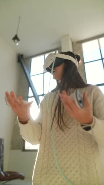 Z założonymi słuchawkami wirtualnej rzeczywistości, młoda kobieta angażuje się w wirtualną grę online. Wysokiej jakości materiał 4k - Materiał filmowy, wideo