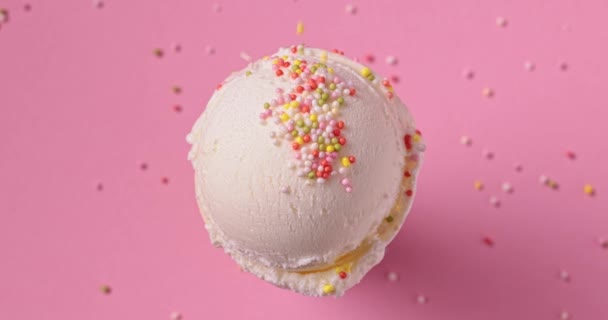 palla di gelato alla vaniglia con gocce di zucchero cadenti su sfondo rosa, vista dall'alto, video al rallentatore - Filmati, video