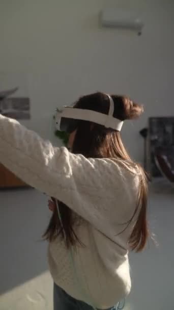 Avec un casque de réalité virtuelle, une jeune fille brillante plonge dans des sessions de jeu en ligne actives. Images 4k de haute qualité - Séquence, vidéo