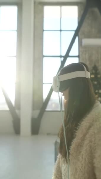 Devant le miroir se tient une charmante jeune femme portant un casque de réalité virtuelle. Images 4k de haute qualité - Séquence, vidéo