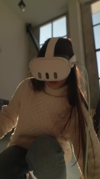 Une belle jeune femme joue à un jeu virtuel en utilisant des lunettes de réalité virtuelle 3D à la maison. Images 4k de haute qualité - Séquence, vidéo