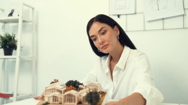 熟練した若い美しい白人建築家リフトハウスモデルを左側と右側に閉じ,青写真で現代のオフィスでミスポイントを検査することに焦点を当てる. インマキュライト. - 映像、動画