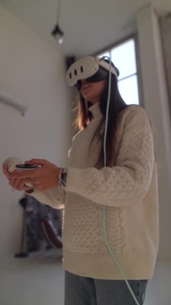 Używając gogli wirtualnej rzeczywistości, młoda kobieta jest zanurzona w wirtualnej grze online. Wysokiej jakości materiał 4k - Materiał filmowy, wideo