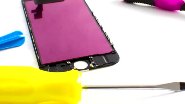 Close-up van een smartphone tijdens het onderhoudsproces op een overzichtelijk oppervlak. Gereedschappen suggereren zorg en precisie. - Video