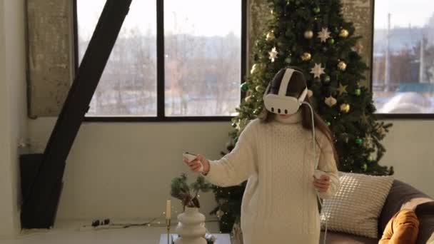 Une jolie jeune femme portant un appareil de réalité virtuelle sur fond d'arbre de Noël. Images 4k de haute qualité - Séquence, vidéo