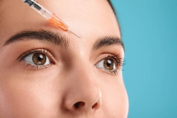 Young woman getting facial injection on light blue background, closeup. Cosmetic surgery - Foto, immagini