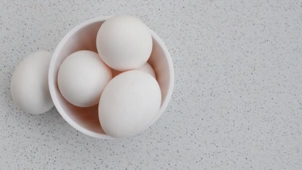 Uroczy szczegół świeżych jaj w misce, zwiększenie czystości na tle światła. Delikatne zbliżenie jaj kurzych w misce, uchwycenie prostoty na oświetlonej powierzchni. - Materiał filmowy, wideo