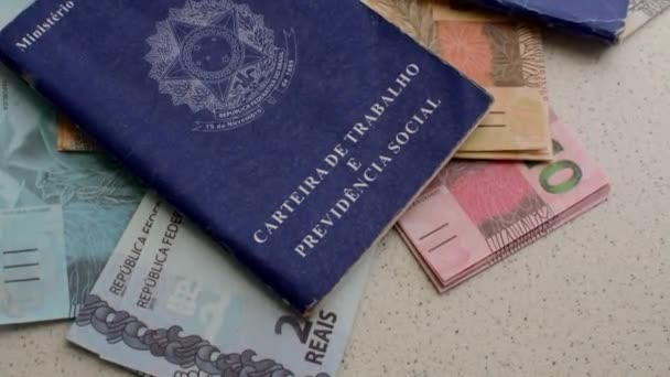 Brazilské ID práce s brazilskou měnou: Vizuální znázornění kariéry a finančního úspěchu, tento obrázek obsahuje brazilské ID práce obklopen brazilských bankovek a mincí. - Záběry, video