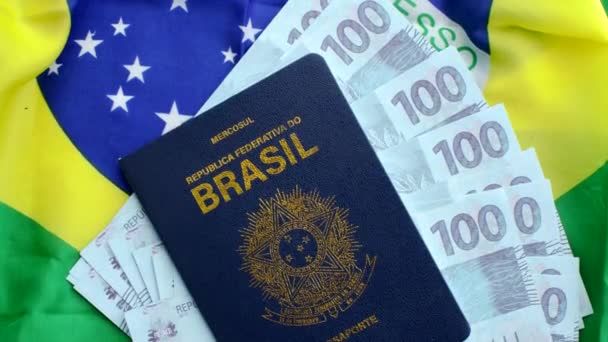 Versión 2: pasaporte brasileño, 100 billetes reales y la bandera nacional. Una imagen que representa la riqueza y la ciudadanía de Brasil. - Imágenes, Vídeo