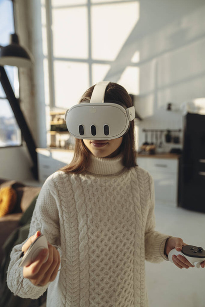 Uma jovem adorável vestindo um fone de ouvido de realidade virtual fala sobre suas impressões. Foto de alta qualidade - Foto, Imagem