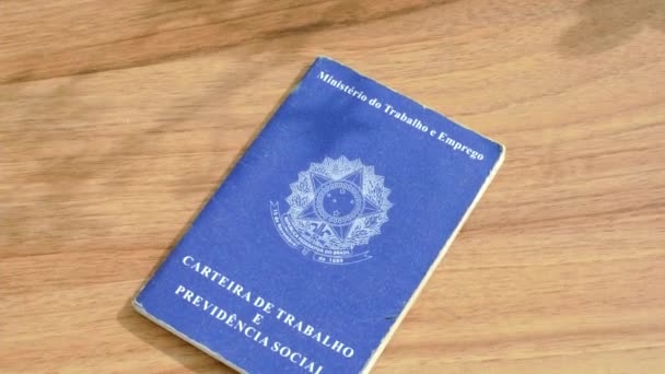 Braziliaanse werk-ID op een houten oppervlak, een emblematische document opnemen van reizen en prestaties. - Video