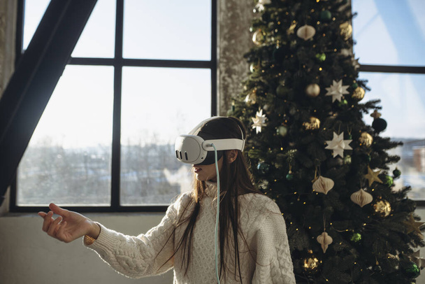 Un ambiente soleado de invierno por la mañana: una joven brillante con un auricular de realidad virtual. Foto de alta calidad - Foto, imagen