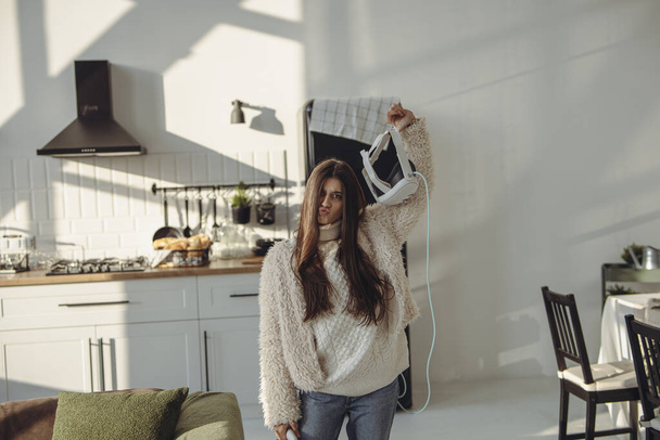 Con gracia, una hermosa joven sostiene un auricular de realidad virtual. Foto de alta calidad - Foto, Imagen
