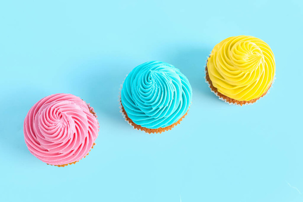 Sabrosos cupcakes de colores sobre fondo azul - Foto, Imagen
