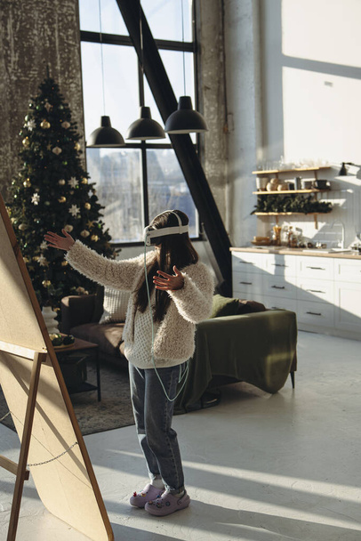Keskellä joulua hurraa, nuori nainen valossa pukea ja VR kuulokkeet ihailee itseään peilistä. Laadukas kuva - Valokuva, kuva