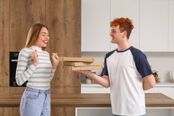 Mladý muž s pizzou žádá svou přítelkyni o ruku v kuchyni - Fotografie, Obrázek