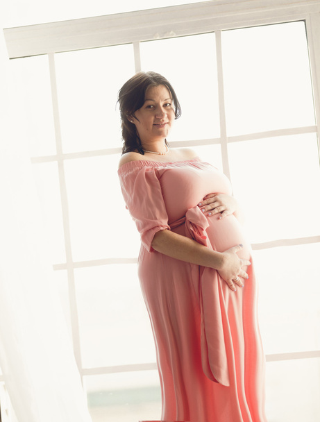 妊婦ブルネット大きなウィンドウに対するポーズのショットをトーンダウン - 写真・画像