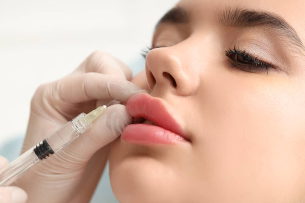 Молодая женщина получает инъекцию губ в салоне красоты, крупным планом - Фото, изображение