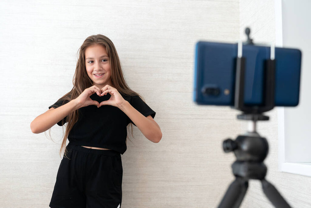 Щаслива молода дівчина блогер перед записом телефонної камери насолоджується танцювальним вмістом у вітальні вдома. Концепція пандемії коронавірусу соціальної відстані. Концепція свободи та активного способу життя - Фото, зображення