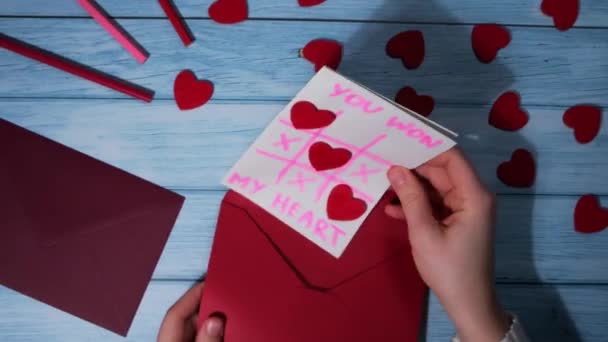Opening making envelope with card for Valentines Day. Text YOU WON MY HEART and tic tac toe game Postcard craft, greeting card. Handmade Valentine greeting card gift with your own hands - Footage, Video