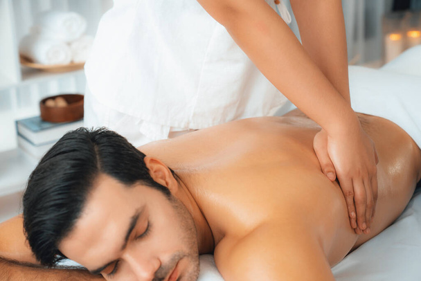 Homme caucasien client appréciant relaxant massage spa anti-stress et dorloter avec beauté loisirs de la peau dans la lumière du jour salon de spa d'ambiance dans un complexe de luxe ou un hôtel. Tranquillité - Photo, image