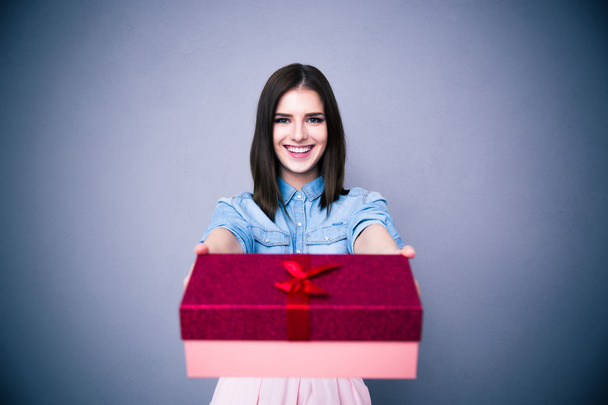 Smiling woman giving a gift box at camera - Fotó, kép