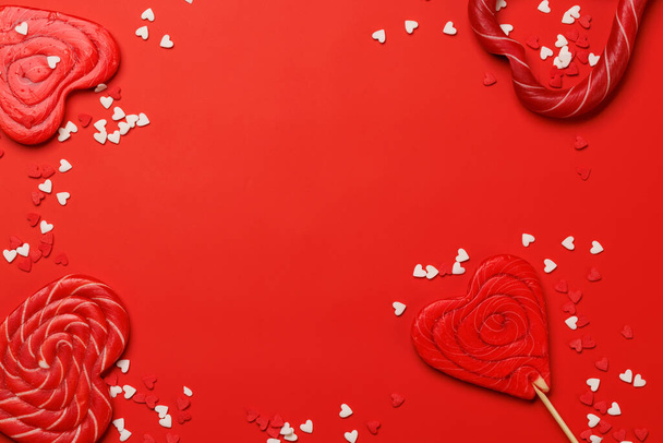 Sucettes de coeur : sucreries sucrées sur fond rouge avec espace de texte. Pose plate carte Saint Valentin - Photo, image