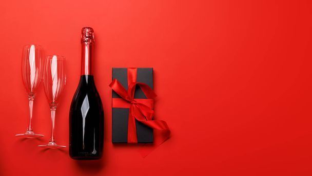 Шампанське і подарунок: святковий дует на червоному тлі з текстовим простором. Вітальна листівка на день Святого Валентина - Фото, зображення