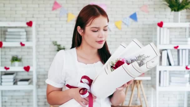 Çekici, Asyalı, aşık genç bir kadın erkek arkadaşından çiçek buketi almış ve çiçekleri mutlu bir şekilde kokluyor. Uluslararası Kadınlar Günü. Sevgililer Günü kutlaması konsepti. - Video, Çekim