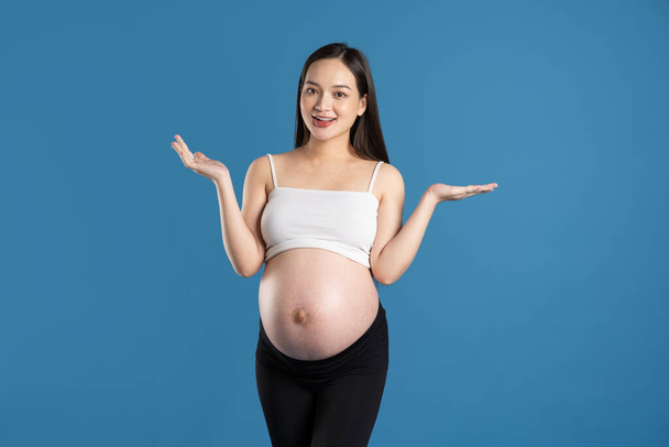 Portret van zwangere aziatische vrouw, geïsoleerd op blauwe achtergrond - Foto, afbeelding