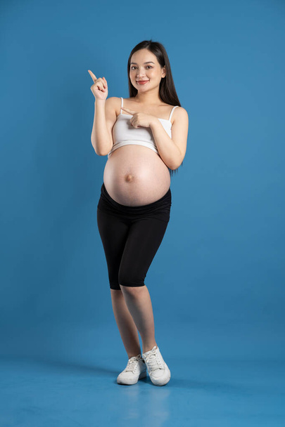 Mavi arka planda izole edilmiş hamile Asyalı kadın portresi. - Fotoğraf, Görsel