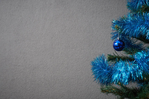 Zdjęcie choinki ozdobionej niebieską zabawką i noworocznym światełkiem do zrobienia pocztówki - Zdjęcie, obraz