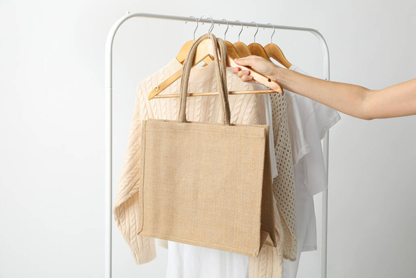 Una bolsa cuelga de una percha con ropa - Foto, Imagen