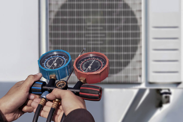 Air conditioning, HVAC service technician using gauges to check refrigerant and add refrigerant. - Photo, Image