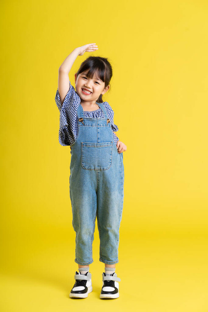 immagine completa del corpo di bella ragazza asiatica bambino su sfondo giallo - Foto, immagini