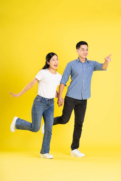 полное изображение азиатской пары, позирующей на желтом фоне - Фото, изображение