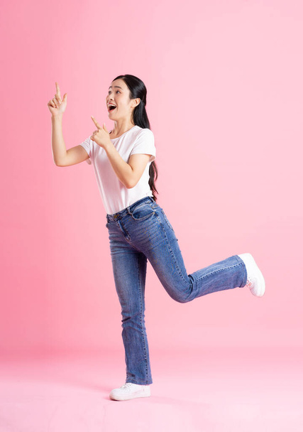 Ganzkörperbild von asiatischen Mädchen posiert auf rosa Hintergrund - Foto, Bild