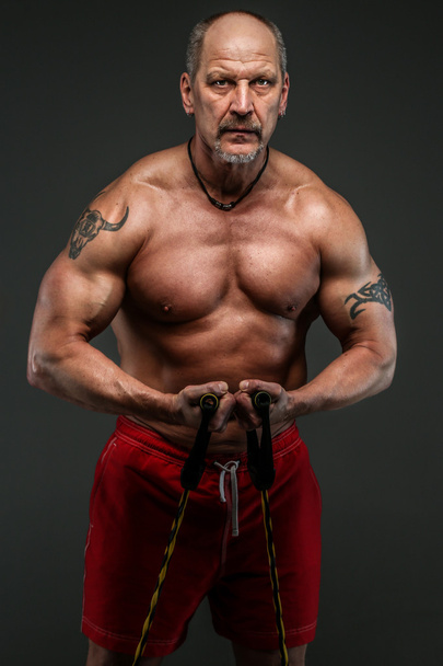 Lihaksikas keski-ikäinen mies osoittaa hänen lihaksia
 - Valokuva, kuva