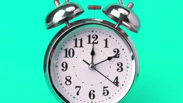 緑の背景に隔離された古典的なヴィンテージの目覚まし時計. 速く動くレトロ警報時計. 時計の手は速く動き,時刻の始まりは12時から1時まで. - 映像、動画